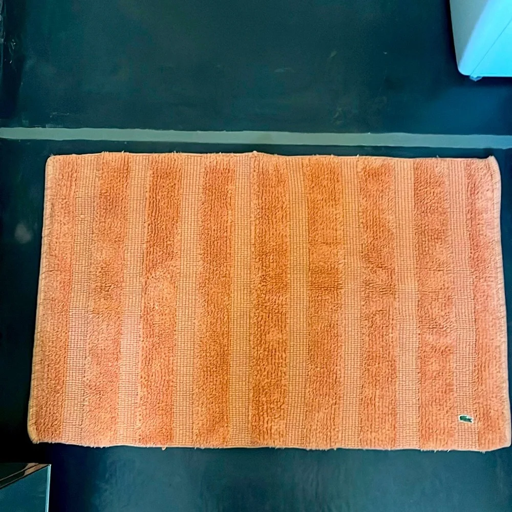 Set of two Lacoste bathroom mats in orange.